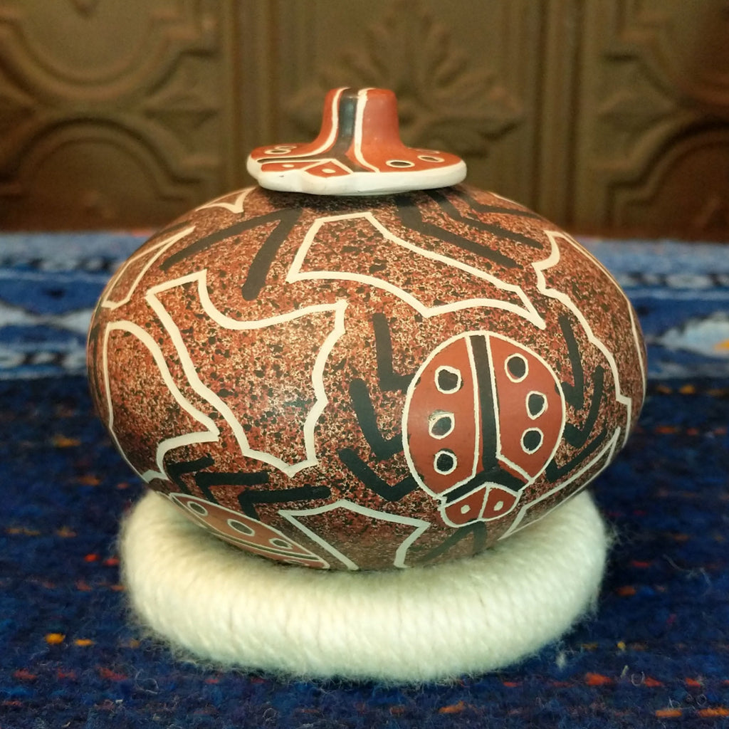 Clay base with red, black, and white designs and ladybug pattern and lid.