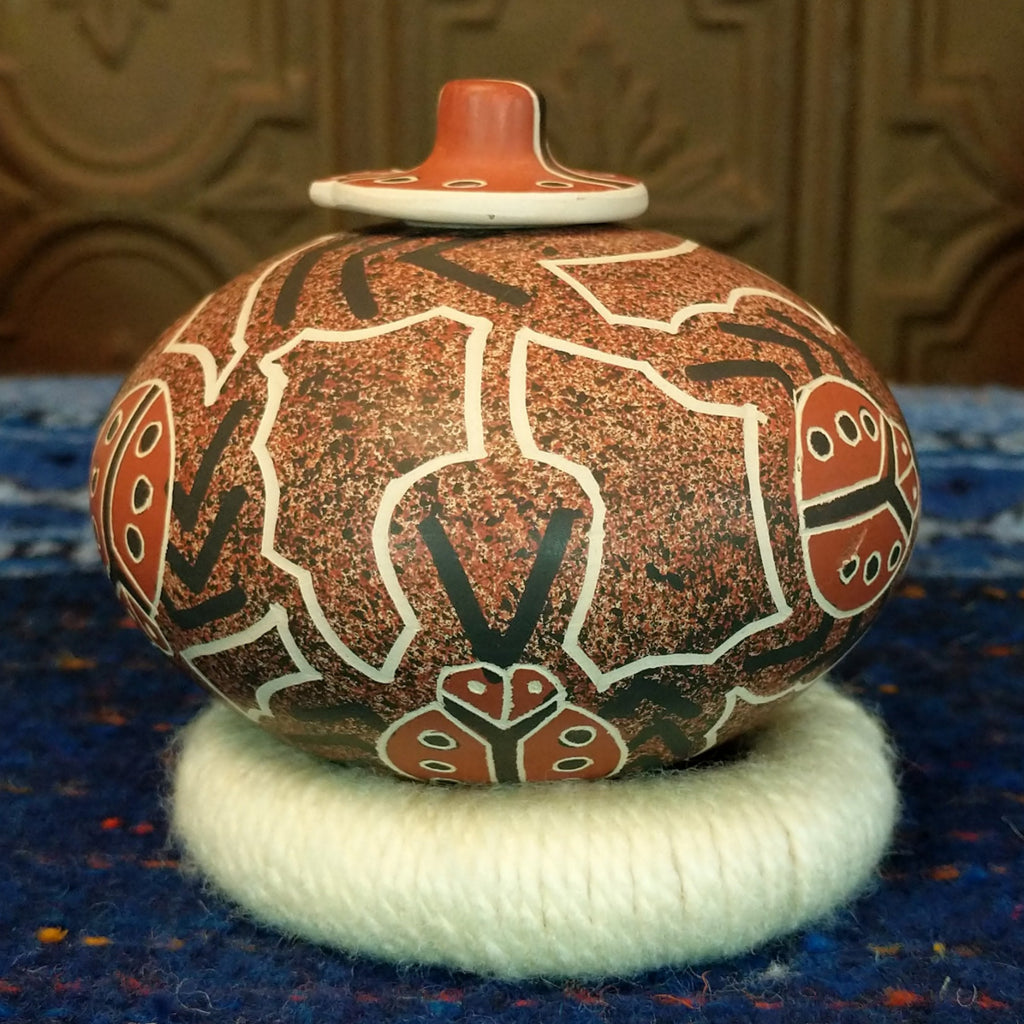 Clay base with red, black, and white designs and ladybug pattern and lid.