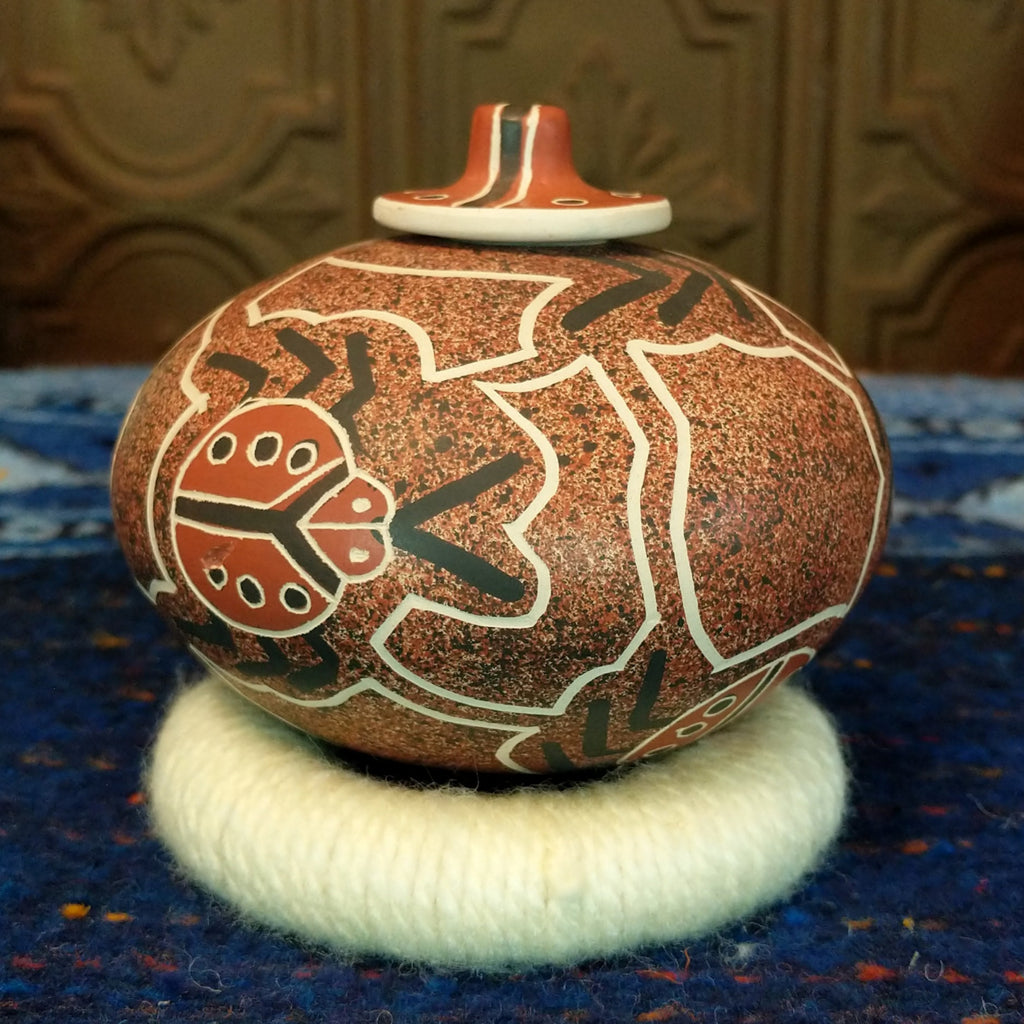Clay base with red, black, and white designs and ladybug pattern and lid.
