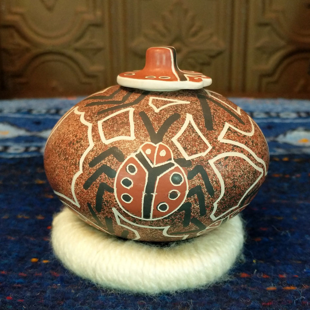 Clay base with red, black, and white designs and ladybug pattern and lid.
