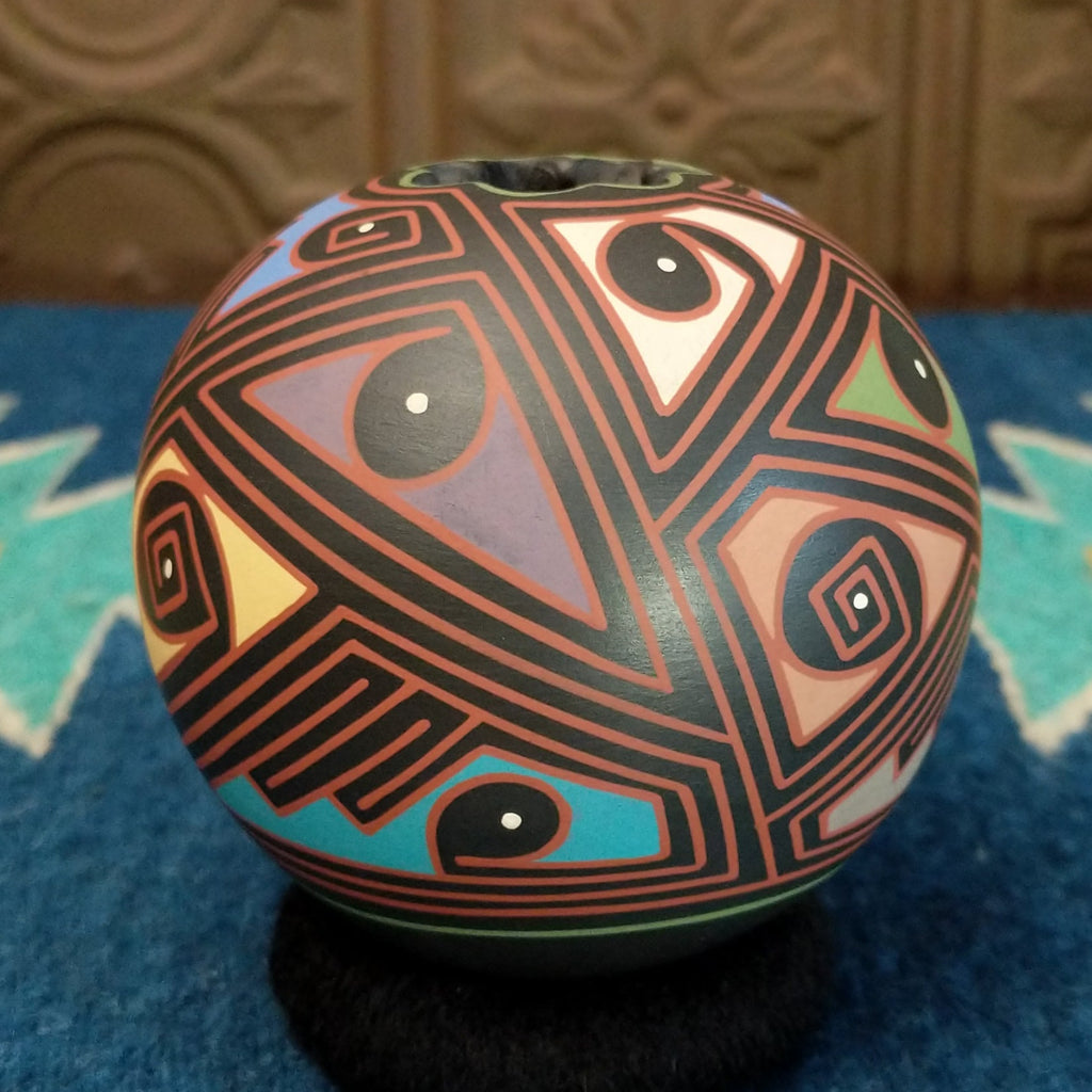 Round clay pottery with colorful and abstract designs.