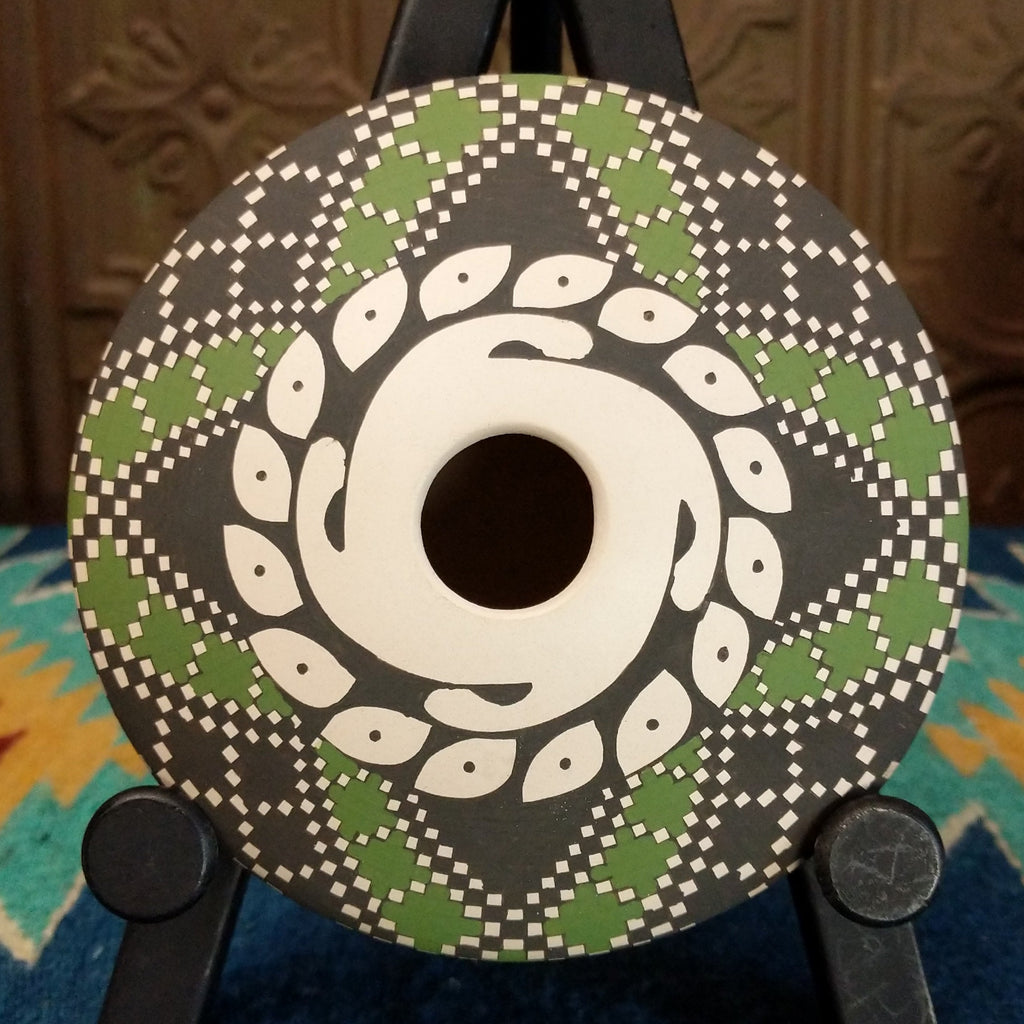 White clay seed pot with symmetrical designs painted in the colors green, black, and white.