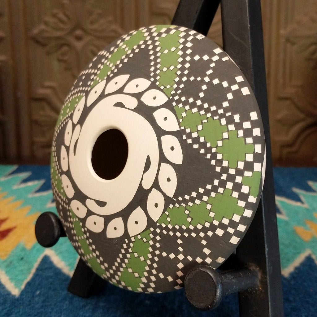 White clay seed pot with symmetrical designs painted in the colors green, black, and white.