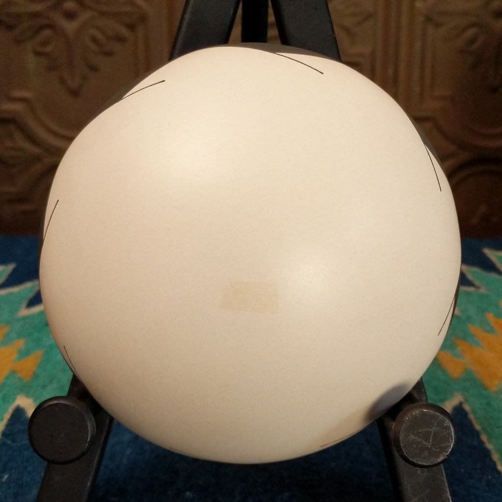 White clay seed pot with symmetrical designs painted in the colors green, black, and white.