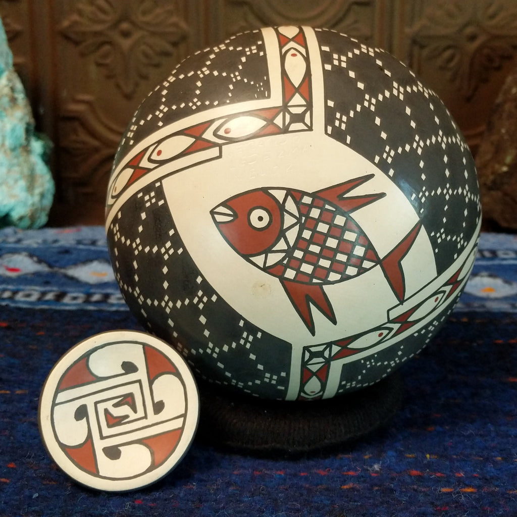 the base of the lid features colorful geometric designs and the base features a fish motif.