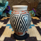 Mata Ortiz pottery vase with a cream rim, featuring bold black and cream triangle spiral patterns with warm clay accents near the neck.