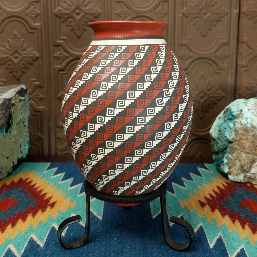 Tritone painted spirals on the clay vase with geometric designs.