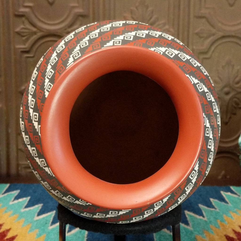 Tritone painted spirals on the clay vase with geometric designs and smooth lip.