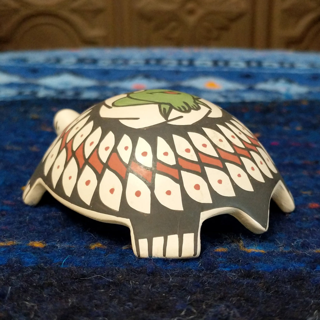 Turtle pottery with black and red designs and a green frog.