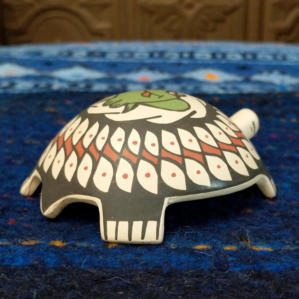 Turtle pottery with black and red designs and a green frog.