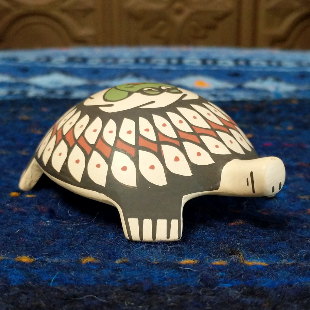 Turtle pottery with black and red designs and a green frog.