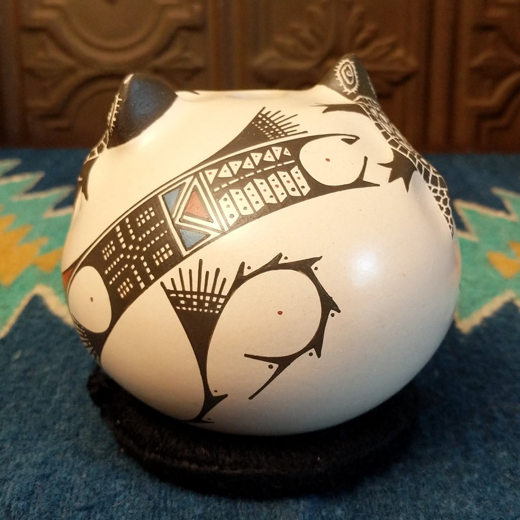 White clay with turtle motifs and geometric designs painted traditional colors on the seed pot.