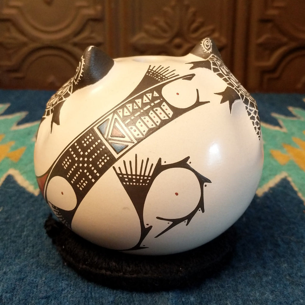 White clay with turtle motifs and geometric designs painted traditional colors on the seed pot.