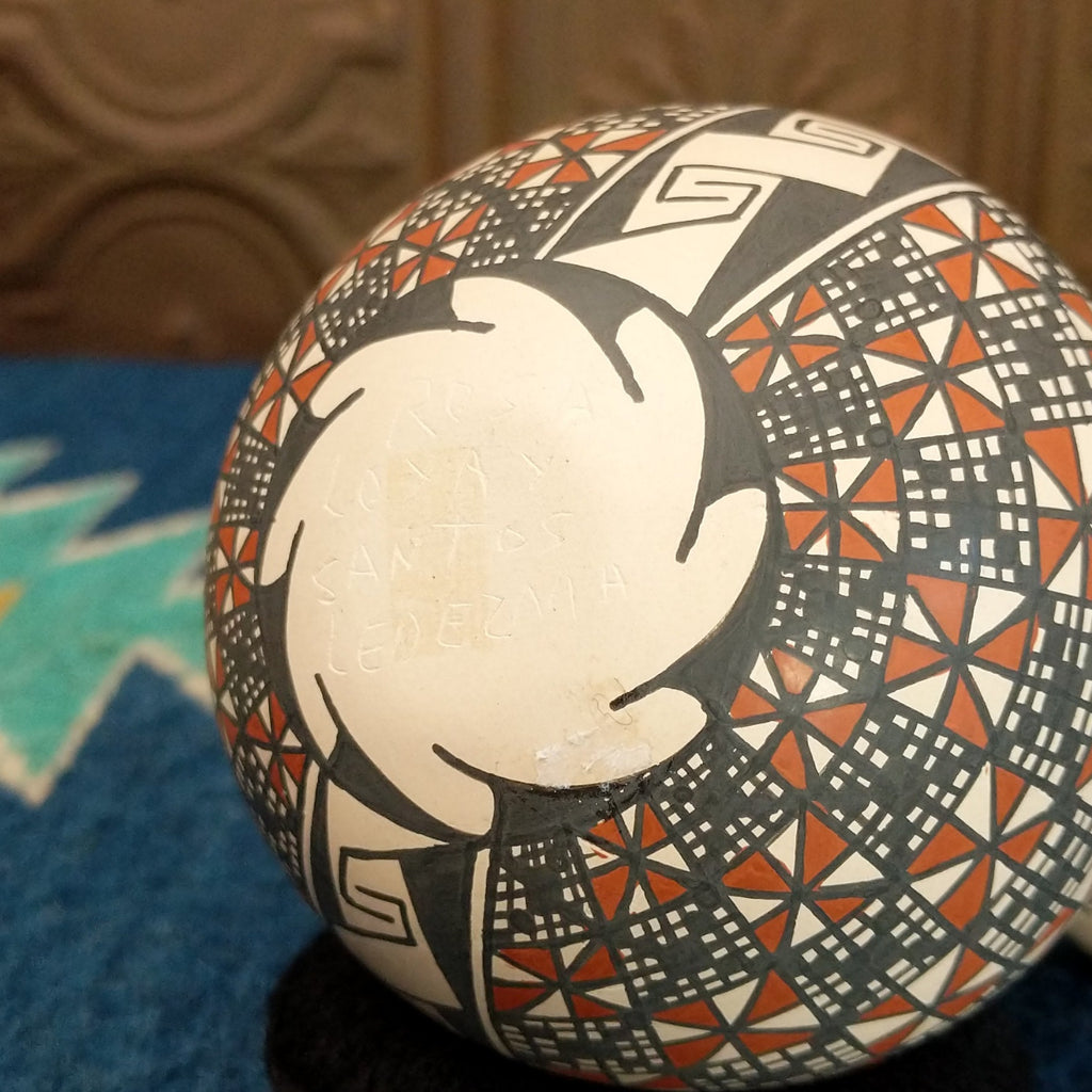 The artisan's signature is at the bottom of the pottery piece.