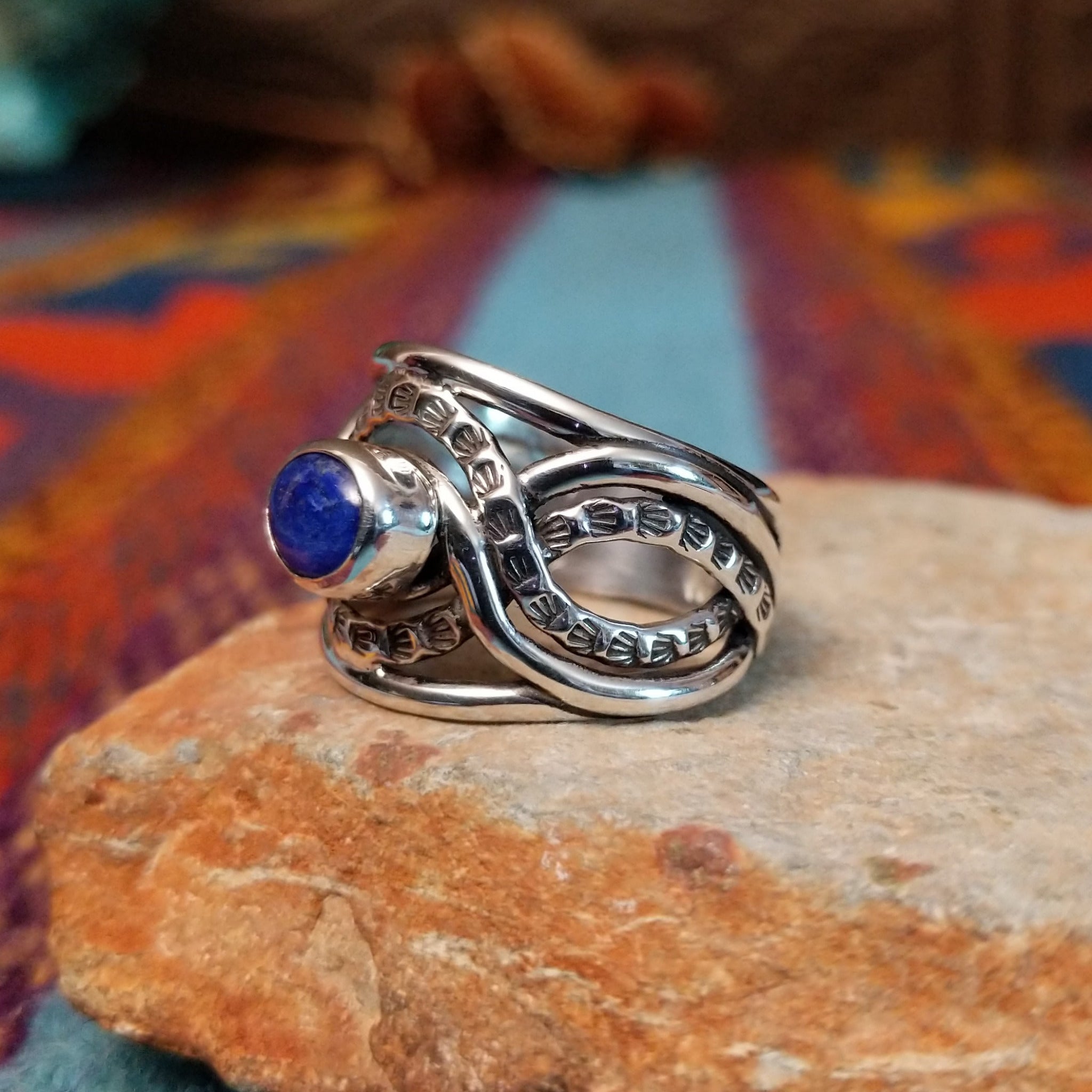 Meandering Lapis Ring by Raymond Coriz featuring an oval blue lapis stone set in Sterling Silver with flowing bands and detailed stamped silver accents; side view.