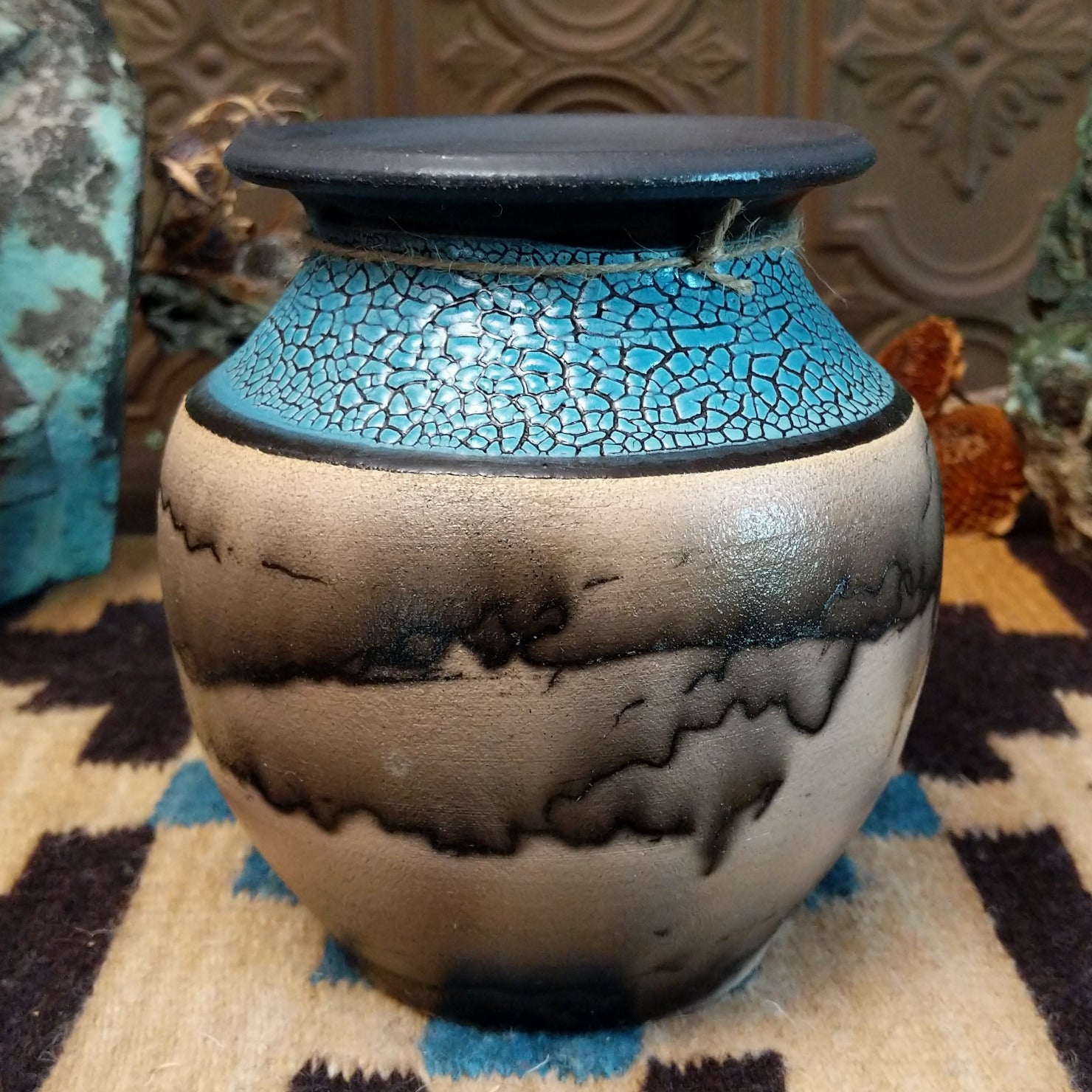 Ceramic pottery piece with horsehair fired onto the face and crackled, blue glazed top-half.