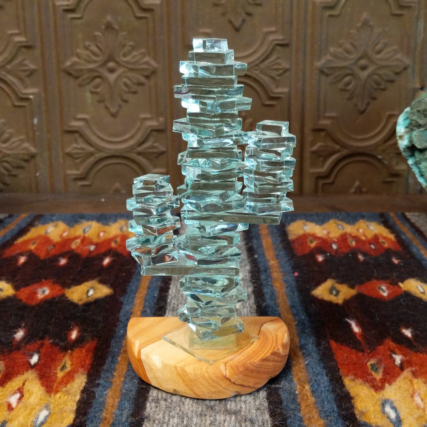 A glass cactus sculpture with translucent aqua glass mounted on a smooth sandstone base.