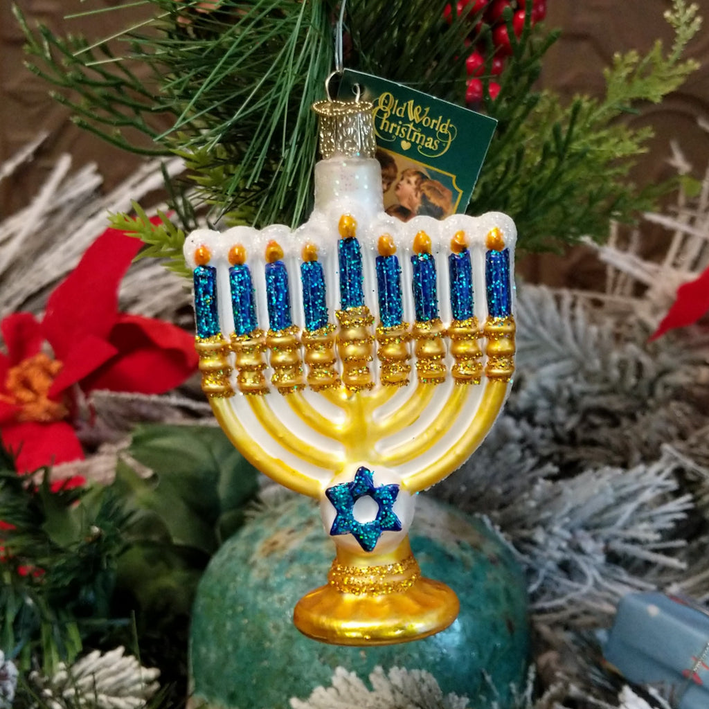 Glass made into a menorah ornament in the colors gold, blue, and white.