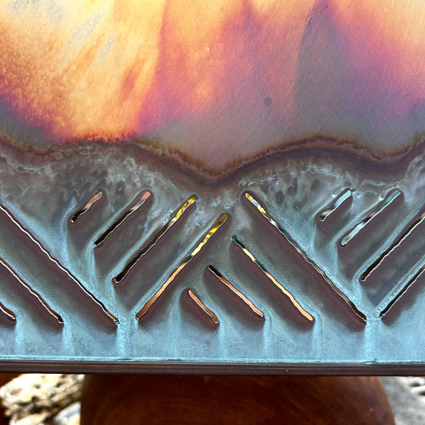 Cutout of mountains on oxidized copper shade.