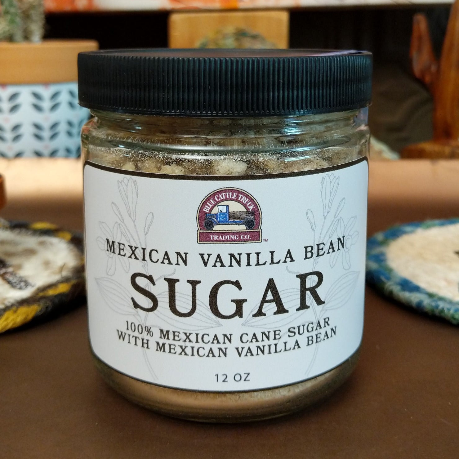 Jar of Mexican Vanilla Bean Sugar featuring fine sugar blended with real vanilla bean specks. Gourmet sweetener with the rich aroma and smooth flavor of authentic Mexican vanilla, ideal for baking and beverages.