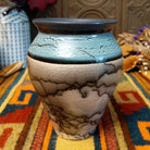 Mini horsehair pottery vase by Roger Calhoun with a flared dark rim, crackled turquoise-blue shoulder, and black horsehair markings concentrated near the base of its cream-colored body.