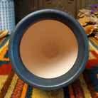 Mini horsehair pottery vase by Roger Calhoun with a flared dark rim, crackled turquoise-blue shoulder, and black horsehair markings concentrated near the base of its cream-colored body.