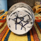 Close-up of the underside of Roger Calhoun's horsehair pottery, showing the artist's hand-painted initials on the unglazed base.