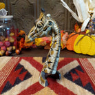 Cast marble used to create a miniature giraffe head painted in traditional colors representing the animal.