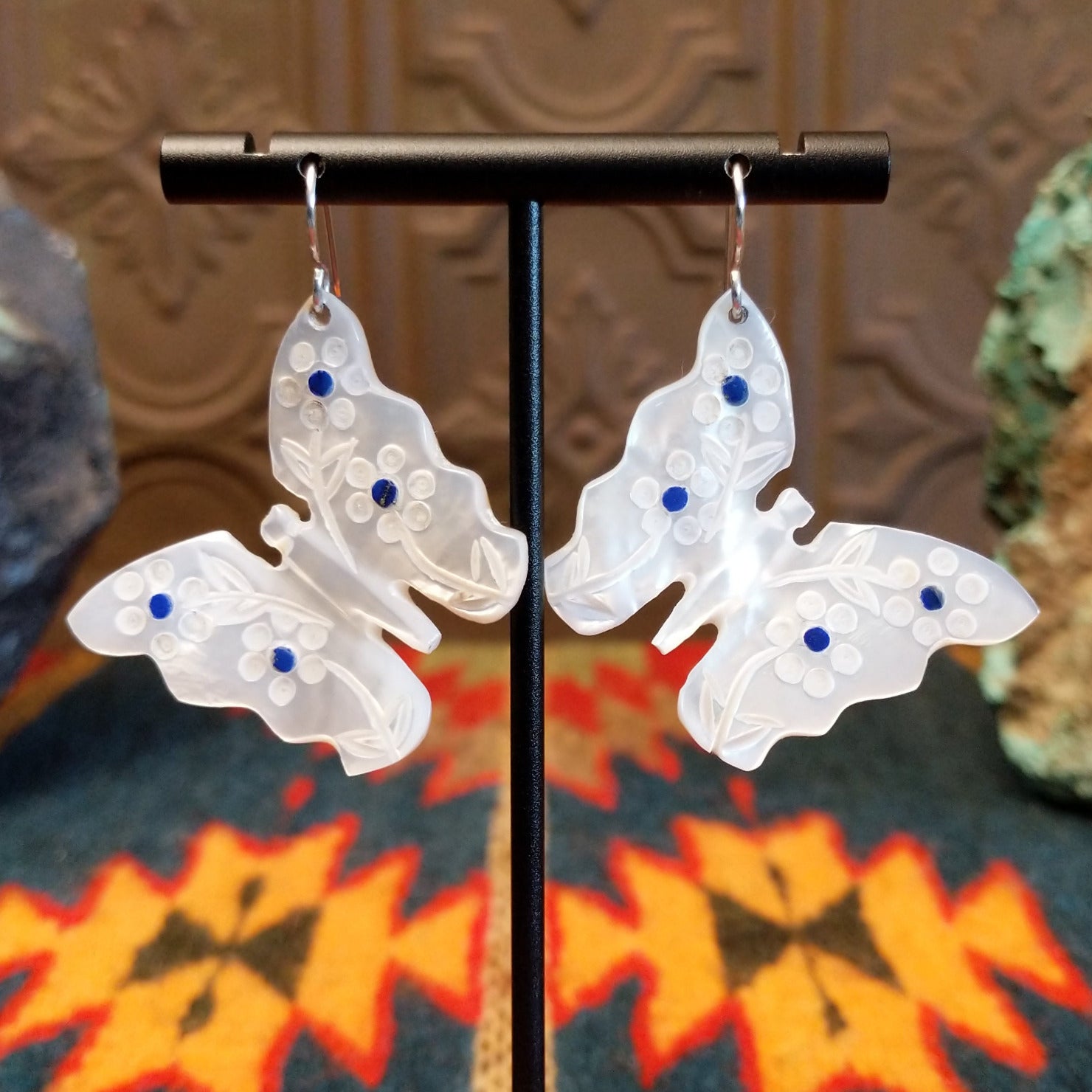 Mother of pearl butterfly earrings with lapis inlaid on the wings, suspended by sterling silver hooks.