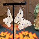 Mother of pearl butterfly earrings with lapis inlaid on the wings, suspended by sterling silver hooks.