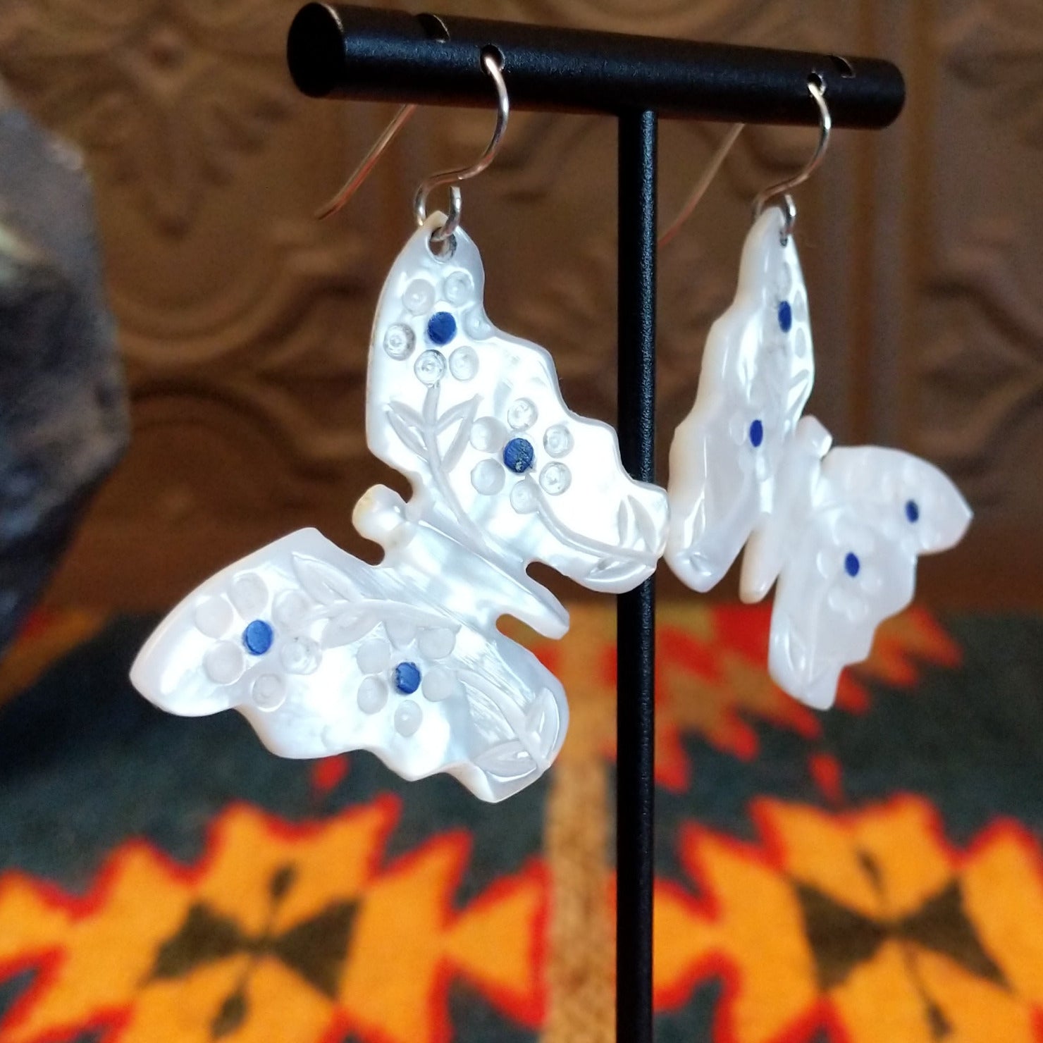 Mother of pearl butterfly earrings with lapis inlaid on the wings, suspended by sterling silver hooks.