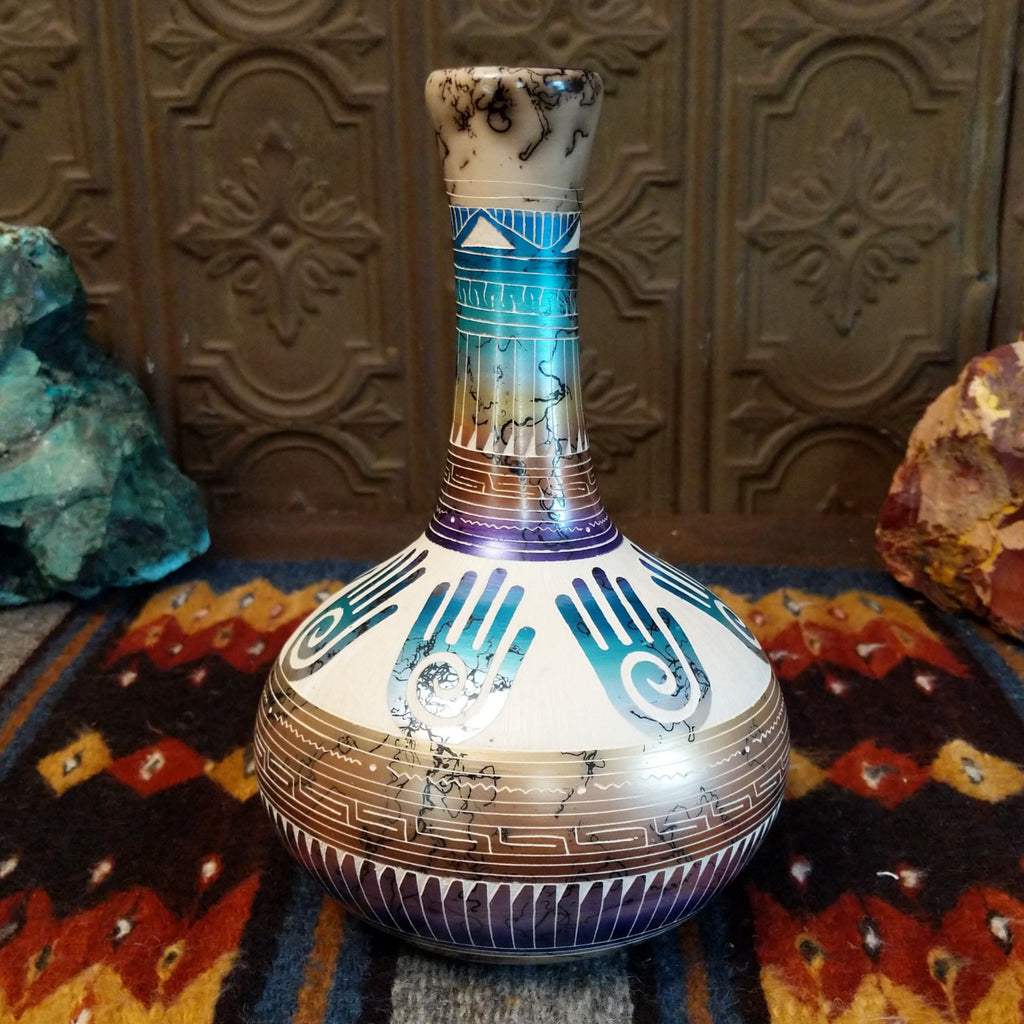 Pottery displaying gradient layers, Hamsa hand motifs, and horsehair texture on white clay.