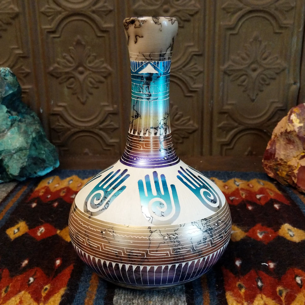 Pottery displaying gradient layers, Hamsa hand motifs, and horsehair texture on white clay.