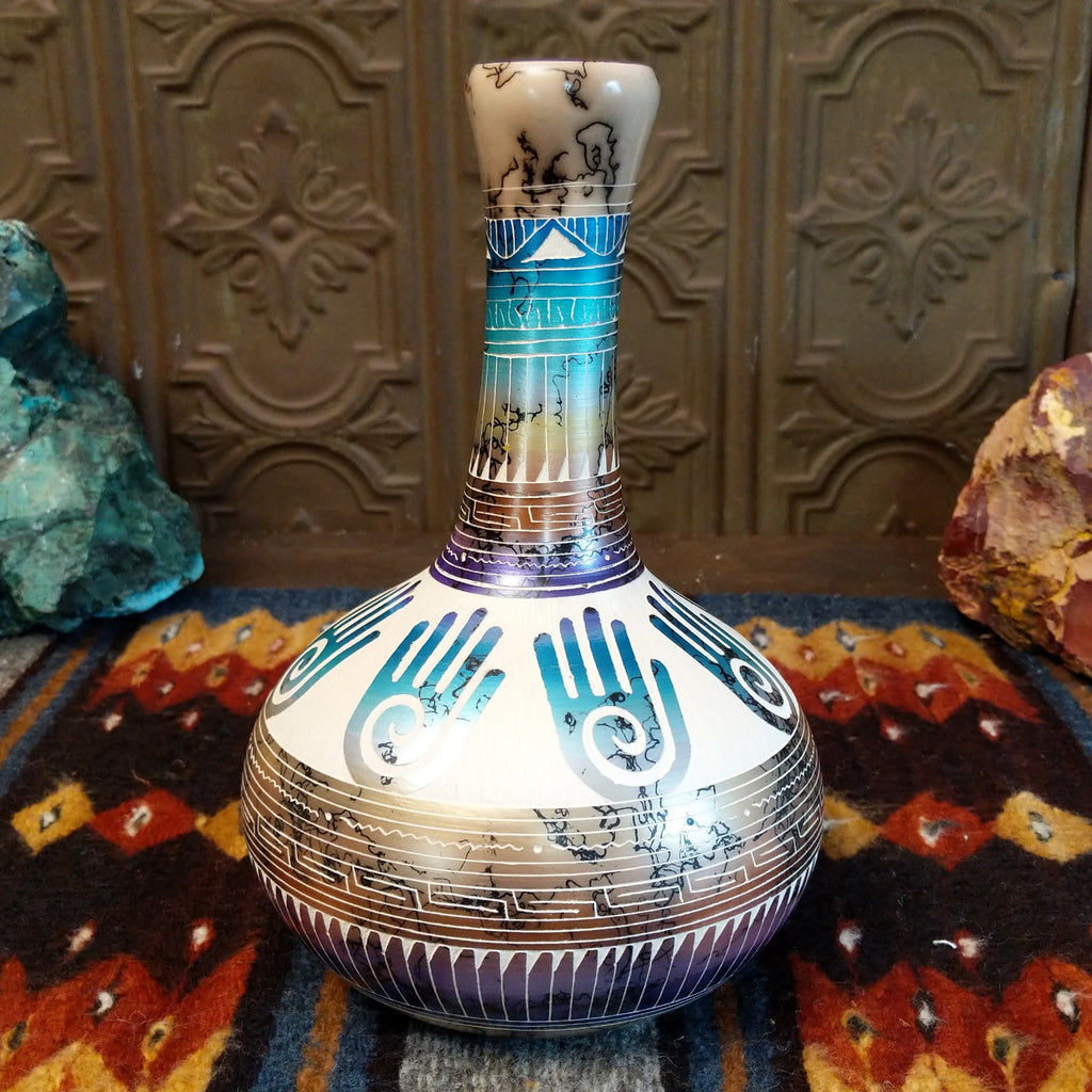 Pottery displaying gradient layers, Hamsa hand motifs, and horsehair texture on white clay.