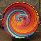 Handwoven multicolor wire art basket by Bridge for Africa featuring a vibrant spiral pattern made from recycled wire in bold rainbow colors, ideal for display or home décor.