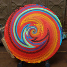Handwoven multicolor wire art basket by Bridge for Africa featuring a vibrant spiral pattern made from recycled wire in bold rainbow colors, ideal for display or home décor; underside view.