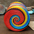 Handwoven multicolor wire art cup by Bridge for Africa featuring vibrant recycled wire in a colorful diagonal pattern, ideal as a decorative container, utensil holder, or pencil cup; underside view.