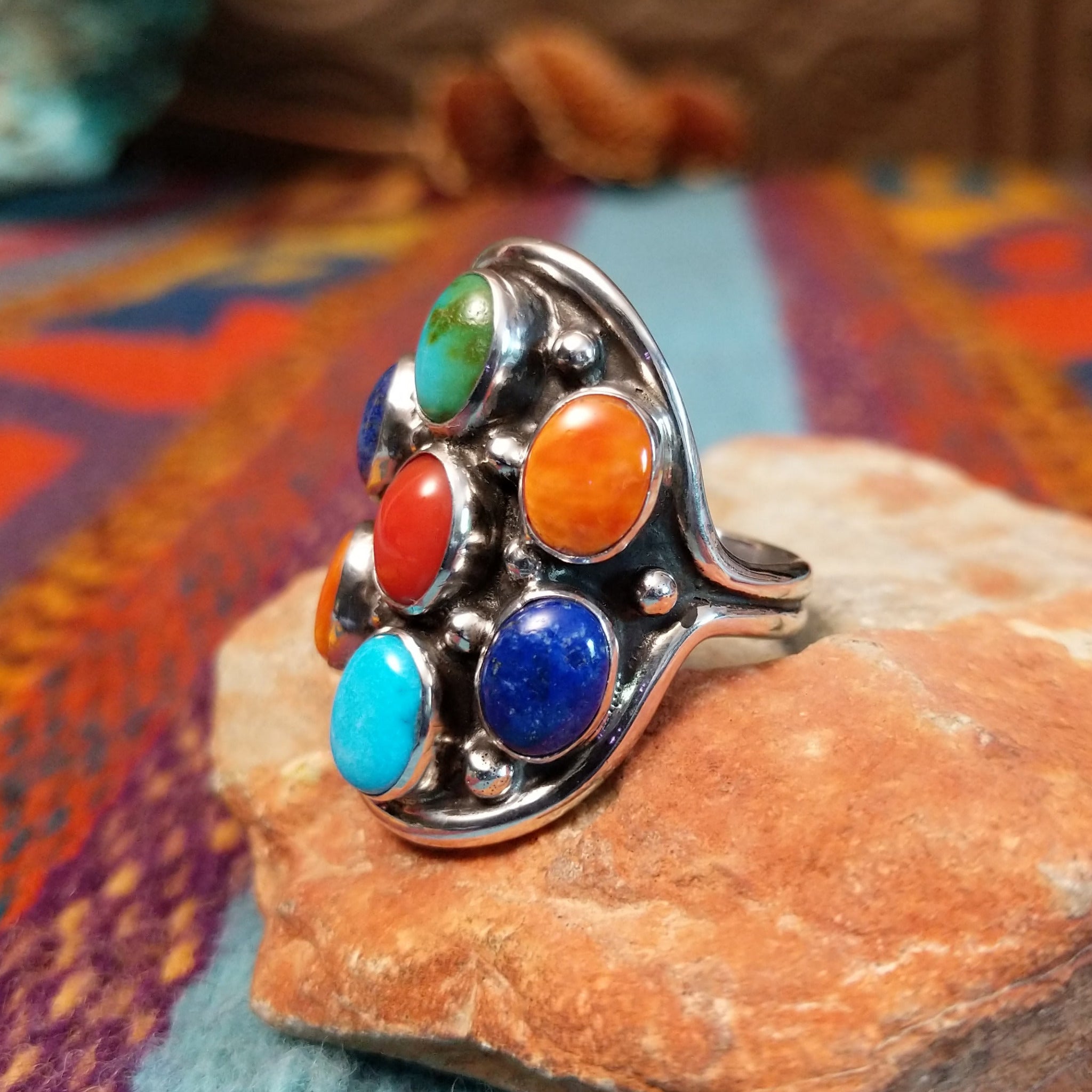 Multistone Cluster Ring by Raymond Coriz featuring turquoise, coral, lapis, and orange-toned stones set in Sterling Silver with polished silver bead accents; side view.