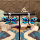 Handcrafted Navajo sterling silver dragonfly earrings by O. James featuring colorful multistone inlay wings in a polished silver dangle design.