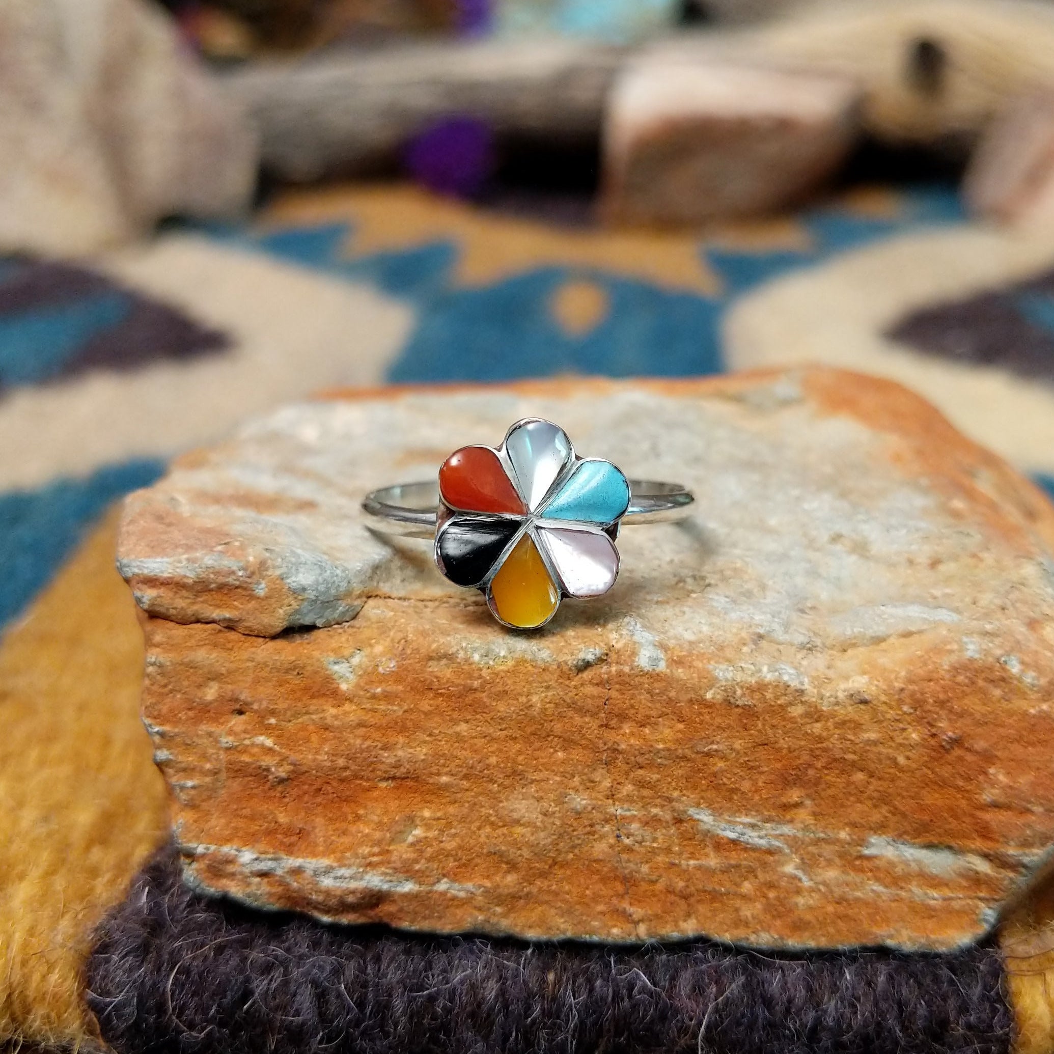 Handcrafted Zuni sterling silver flower ring by Raymond Bobelu featuring a six-petal multistone inlay design with turquoise, coral, black onyx, mother of pearl, and yellow mussel shell.