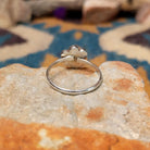 Handcrafted Zuni sterling silver flower ring by Raymond Bobelu featuring a six-petal multistone inlay design with turquoise, coral, black onyx, mother of pearl, and yellow mussel shell; underside view.