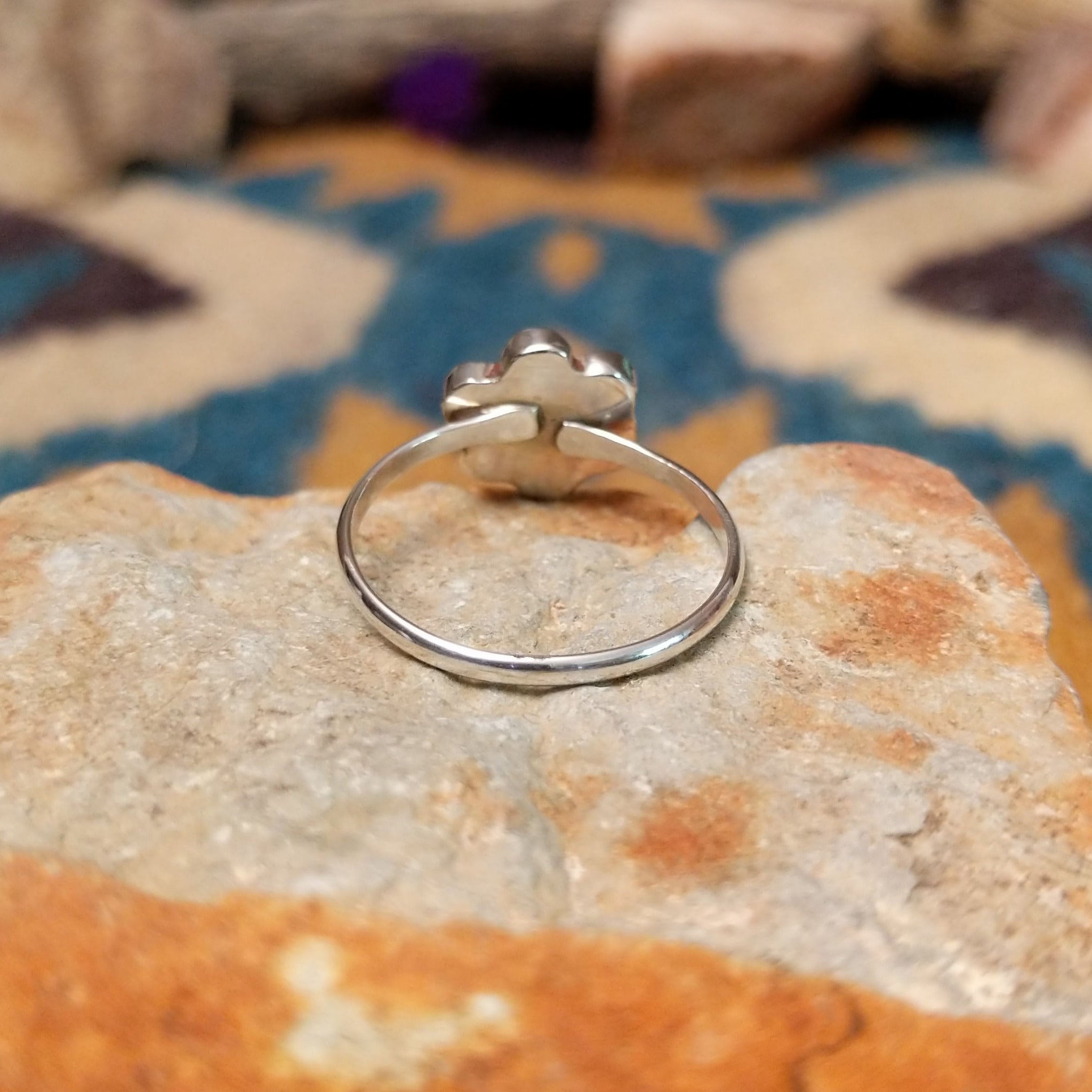 Handcrafted Zuni sterling silver flower ring by Raymond Bobelu featuring a six-petal multistone inlay design with turquoise, coral, black onyx, mother of pearl, and yellow mussel shell; underside view.