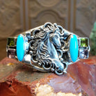 Sterling silver cuff bracelet with horse motif and turquoise, peridot, and amethyst set in bezels.