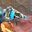 Sterling silver cuff bracelet with horse motif and turquoise, peridot, and amethyst set in bezels.