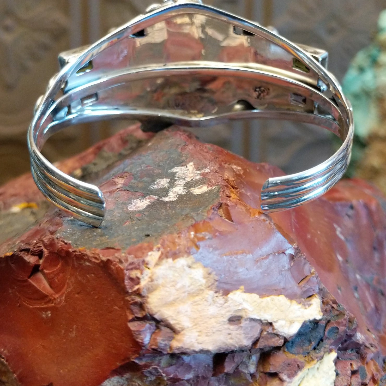 Sterling silver cuff bracelet with horse motif and turquoise, peridot, and amethyst set in bezels.
