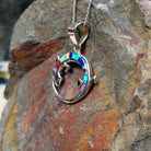 Multistone inlay lizard pendant by Ambrose Tsosie featuring a circular sterling silver lizard design accented with turquoise, blue, red, purple, and cream-colored stone inlay; side view.