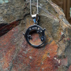 Multistone inlay lizard pendant by Ambrose Tsosie featuring a circular sterling silver lizard design accented with turquoise, blue, red, purple, and cream-colored stone inlay; artisan and Sterling Silver stamp.