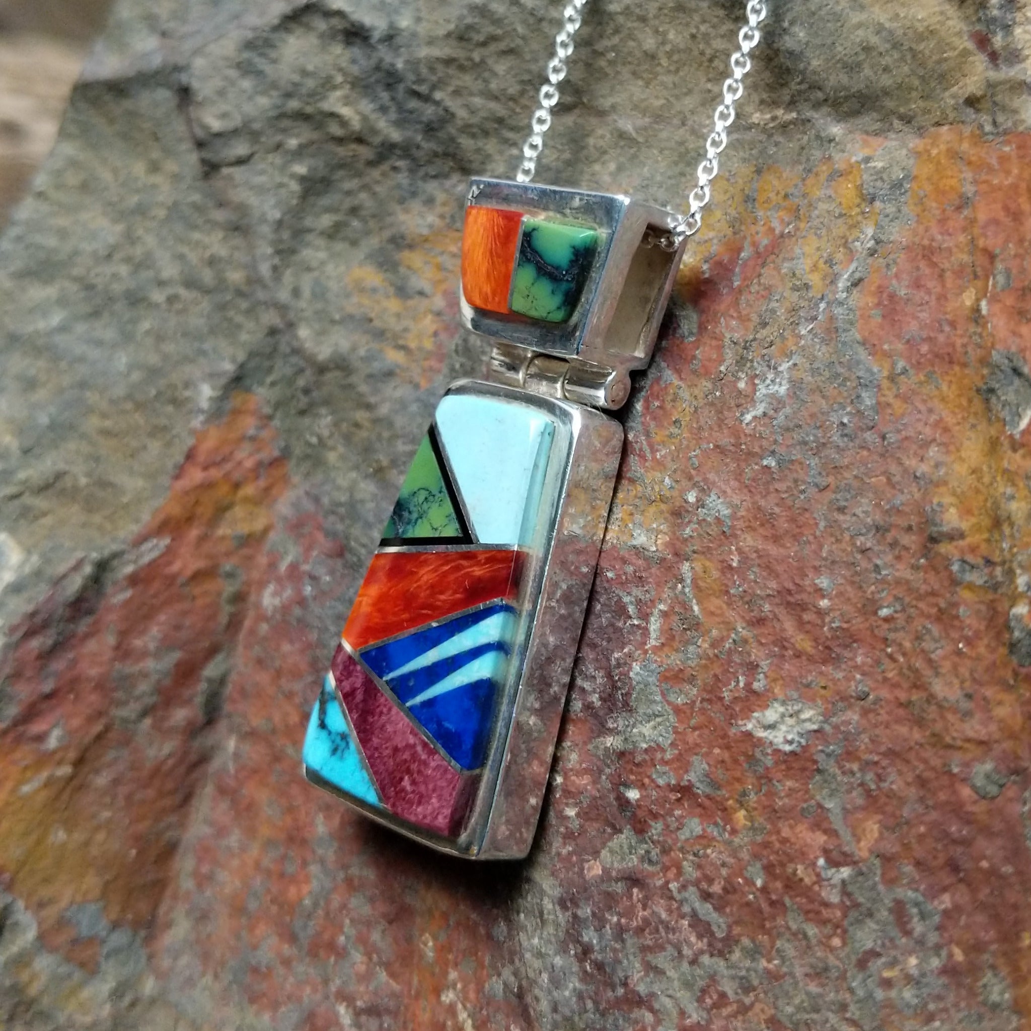Handcrafted sterling silver multistone inlay pendant by Valerie Yazzie, featuring a colorful geometric inlay design with an articulated two-piece pendant; side view.