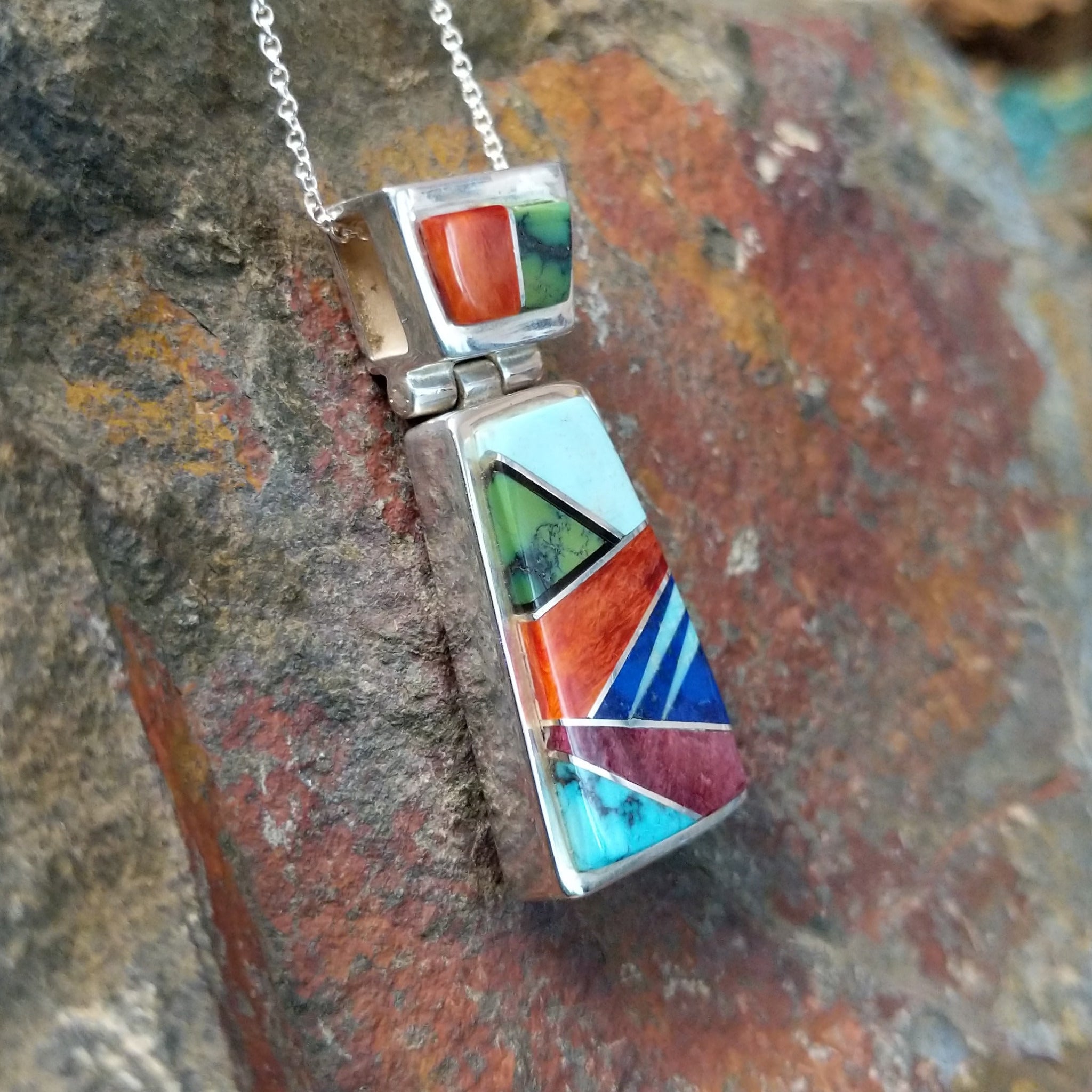 Handcrafted sterling silver multistone inlay pendant by Valerie Yazzie, featuring a colorful geometric inlay design with an articulated two-piece pendant; side view.
