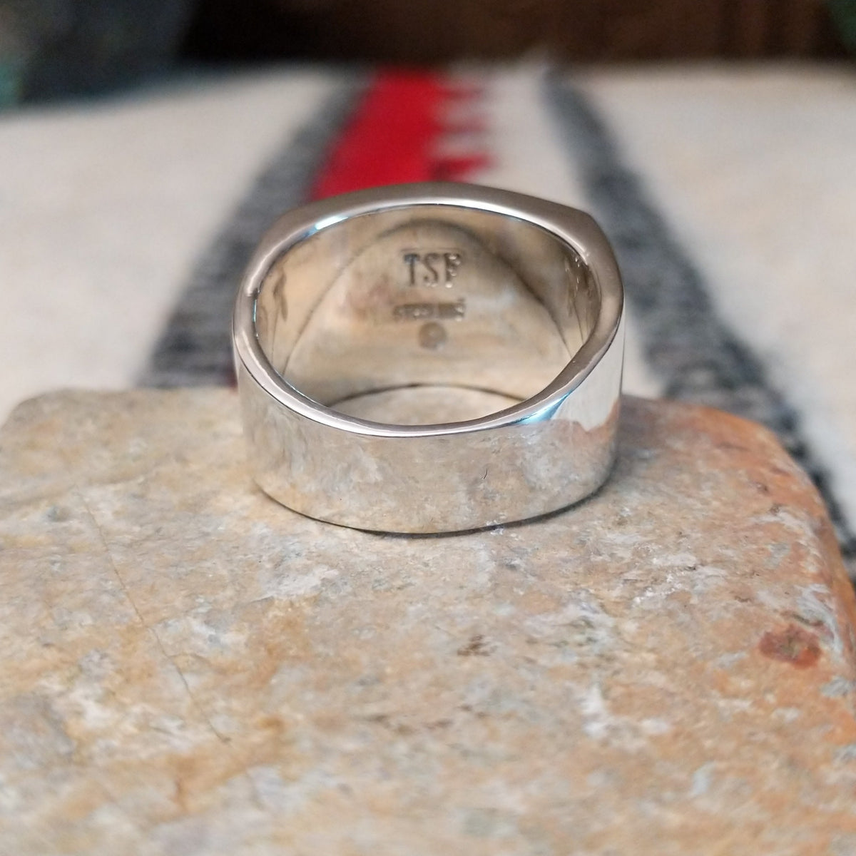 Multistone inlay ring by E.D. featuring geometric turquoise, blue, purple, black, and light-colored stones separated by fine silver channels in a wide polished silver setting; underside view.